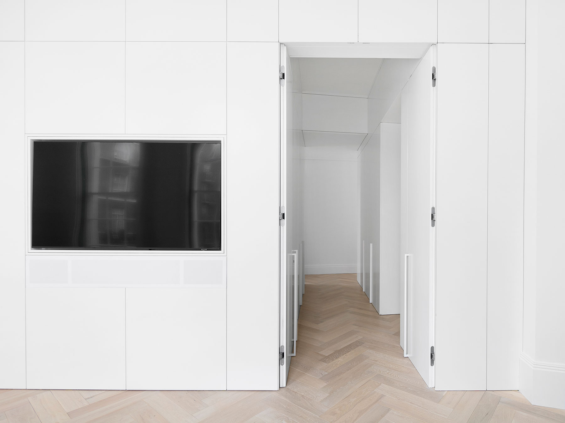 Extensive wrap-around joinery throughout this hallway, with full height bespoke doors featuring concealed hinges